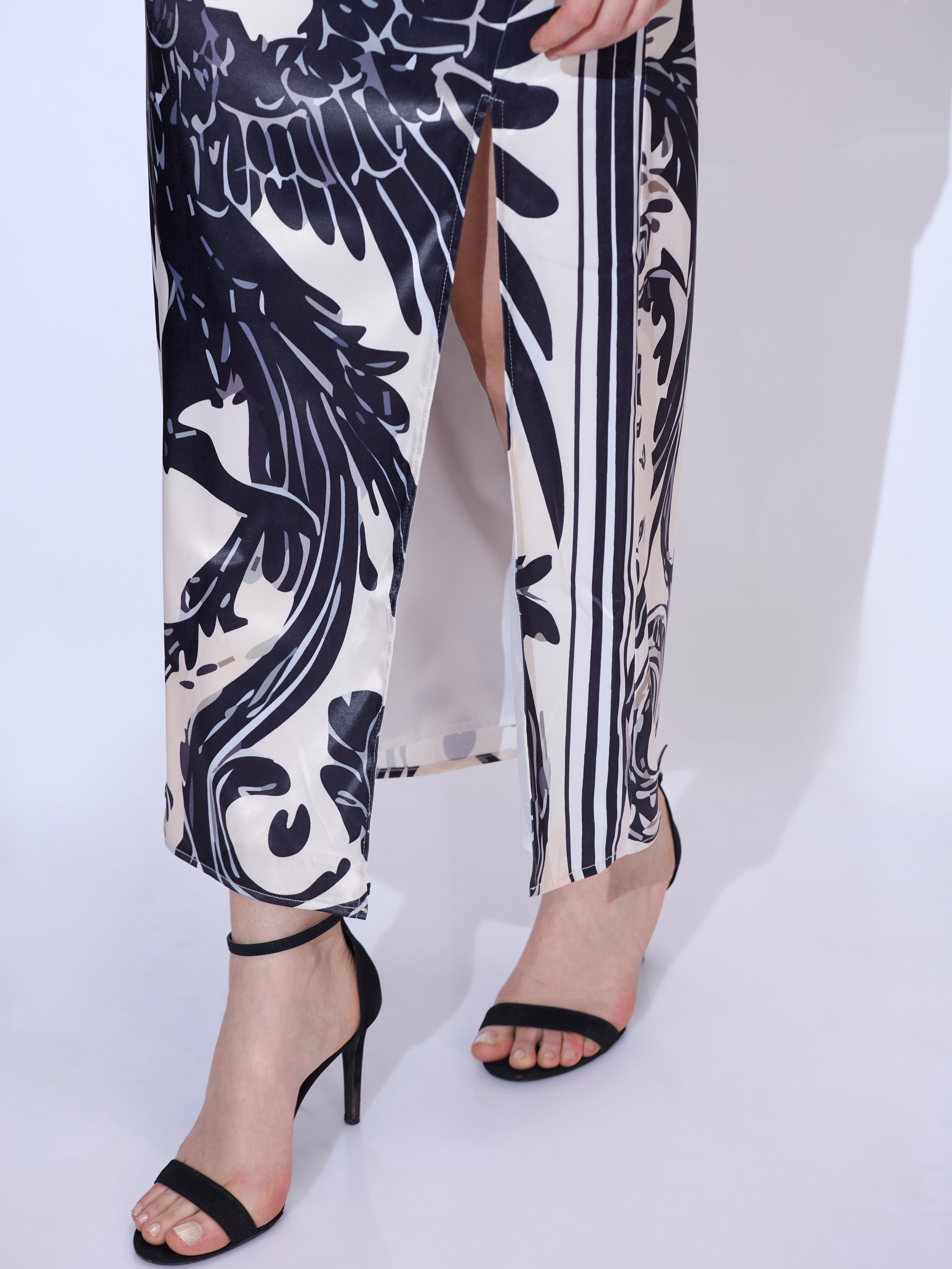 Image of Close-up of legs in a black and white maxi dress with dragon print and high side slit