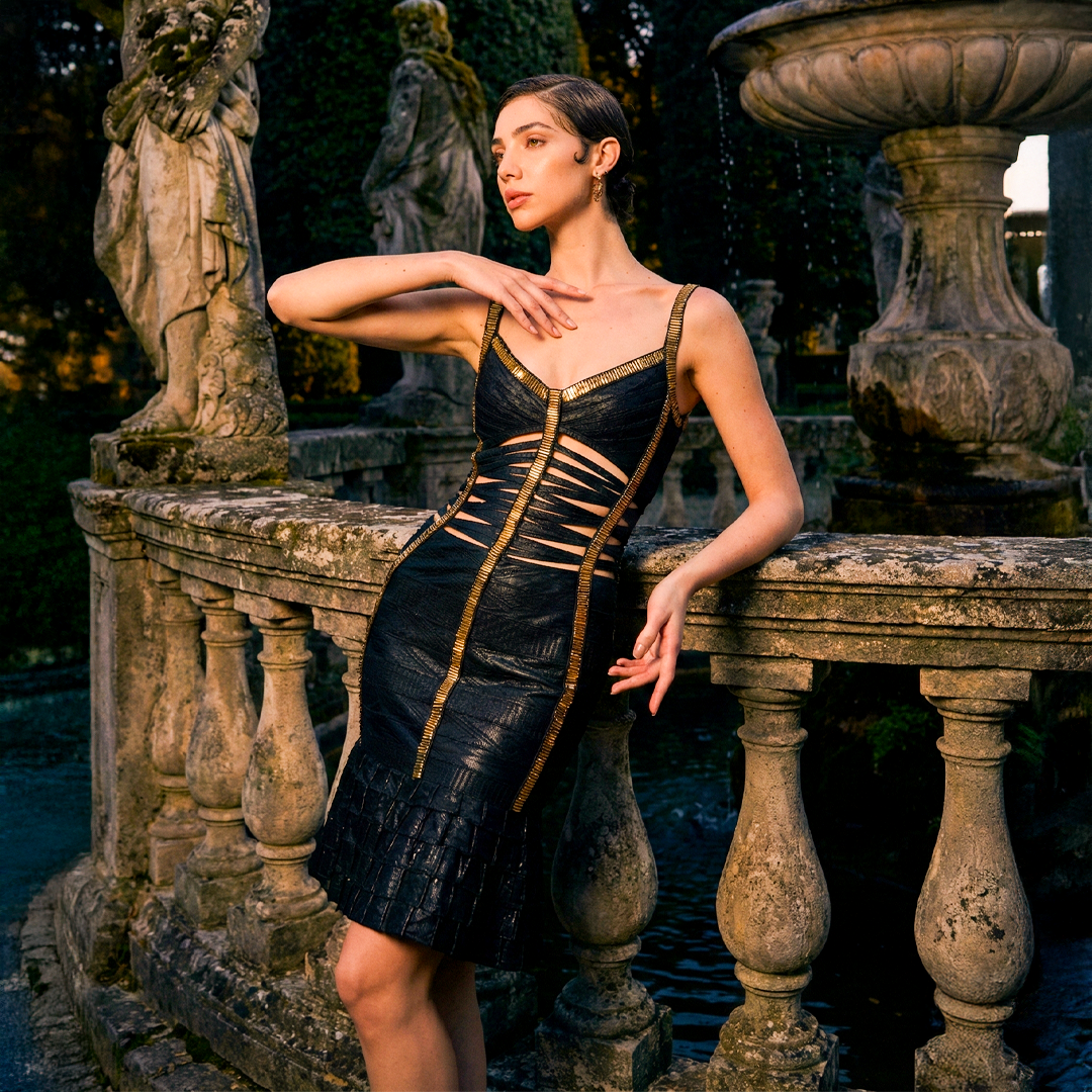 Image of Black bandage dress with gold trim, sweetheart neckline, midriff cut-outs, and tiered ruffle mermaid hem.