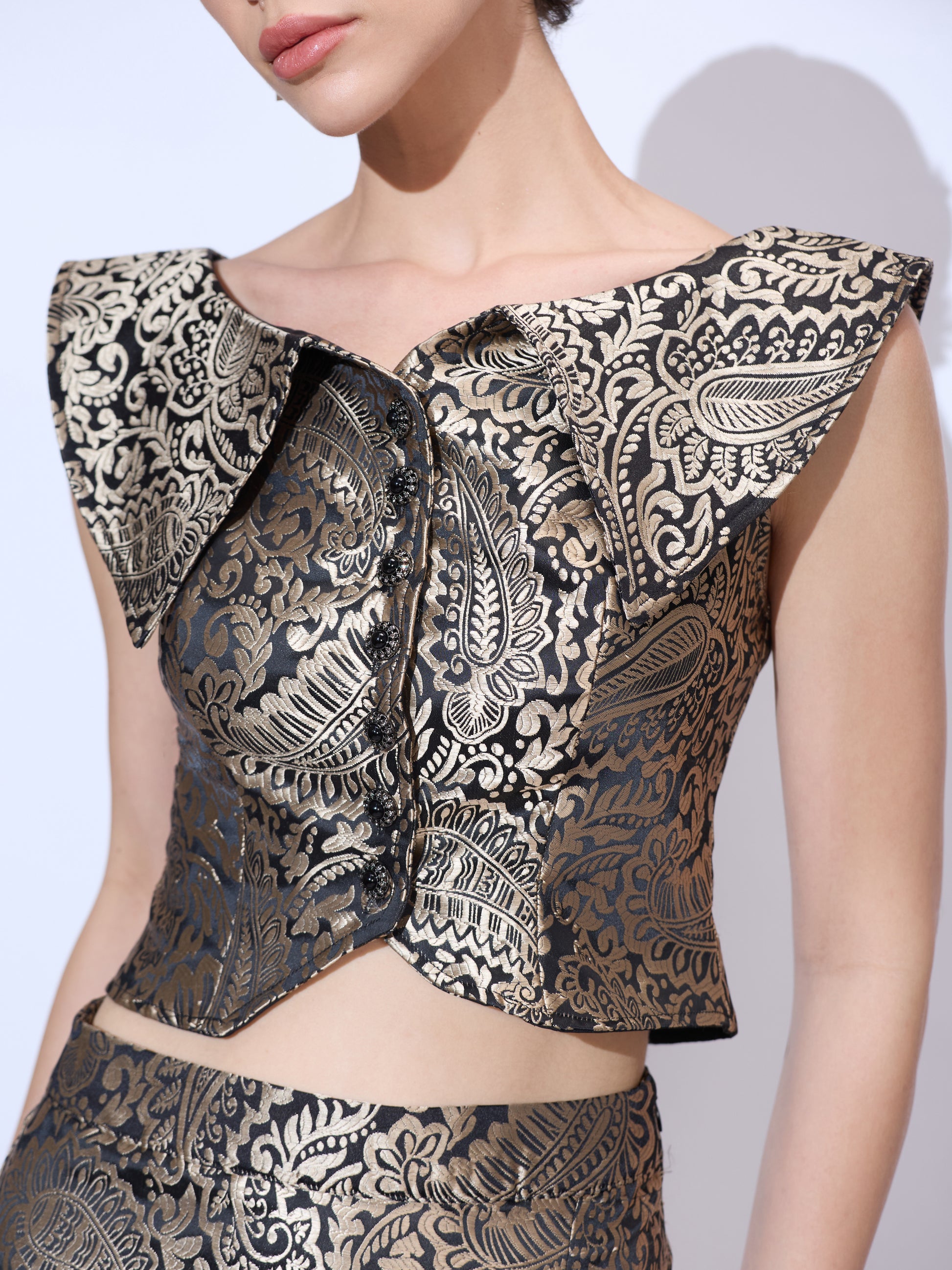 Close-up of black and gold metallic paisley brocade co ord set featuring a cropped top with ruffled neckline detail