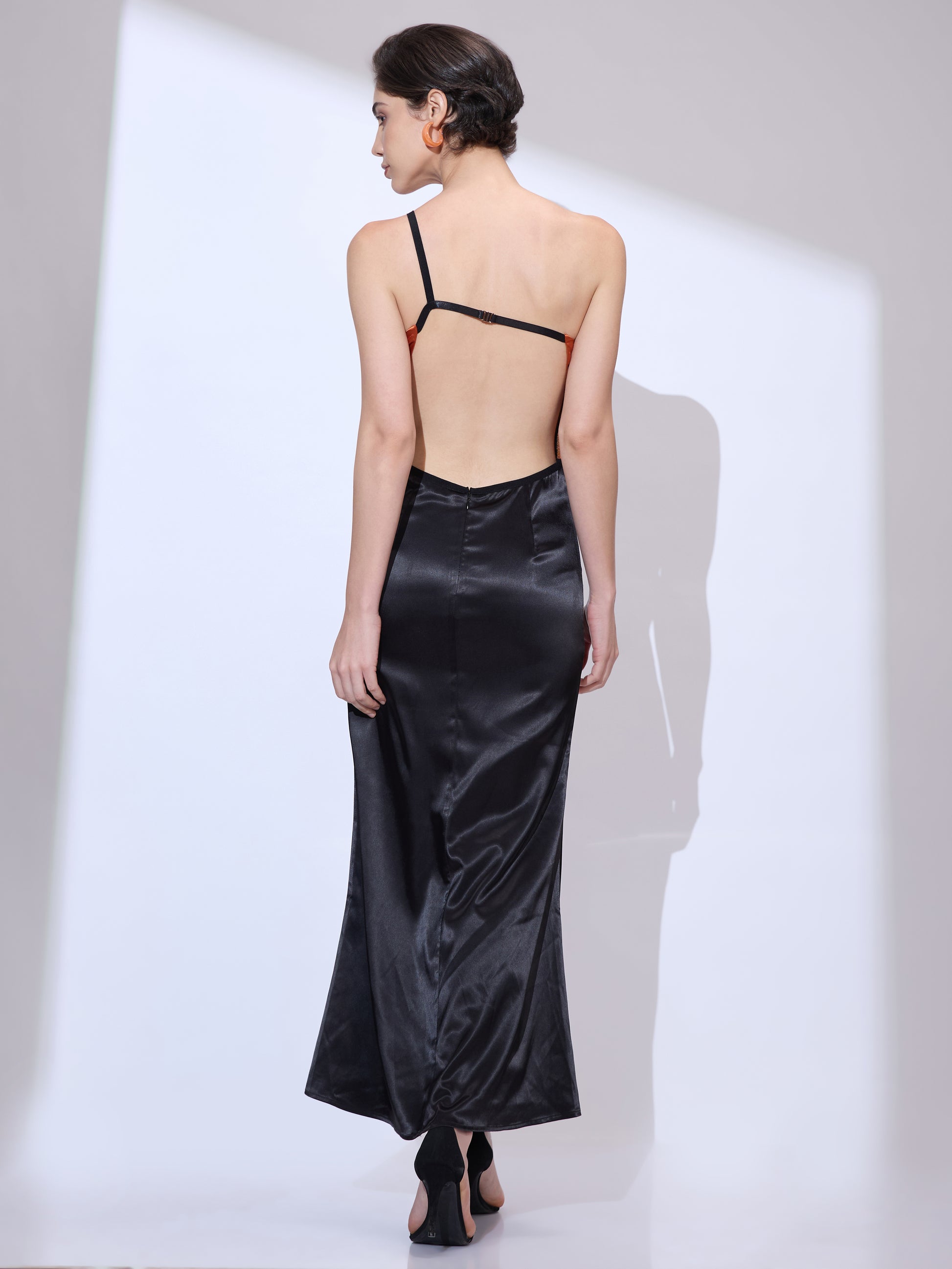 Back view of woman wearing a black silk satin cowl neck maxi dress with elegant low back design
