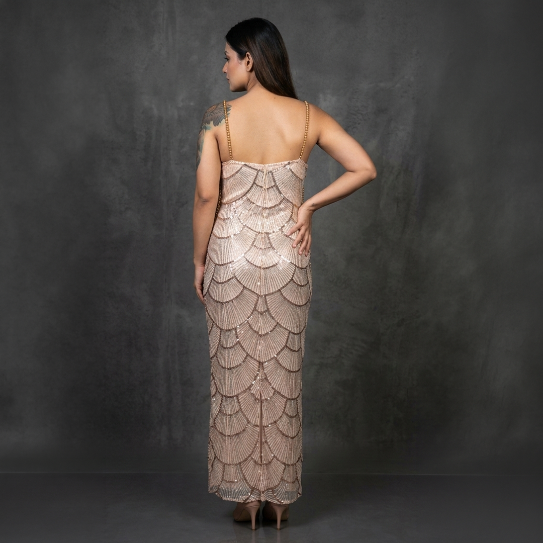 Image of Back view of woman wearing Bronze Pearl Embellished Mermaid Maxi Dress with hand-embellished pearl detailing and mermaid silhouette.