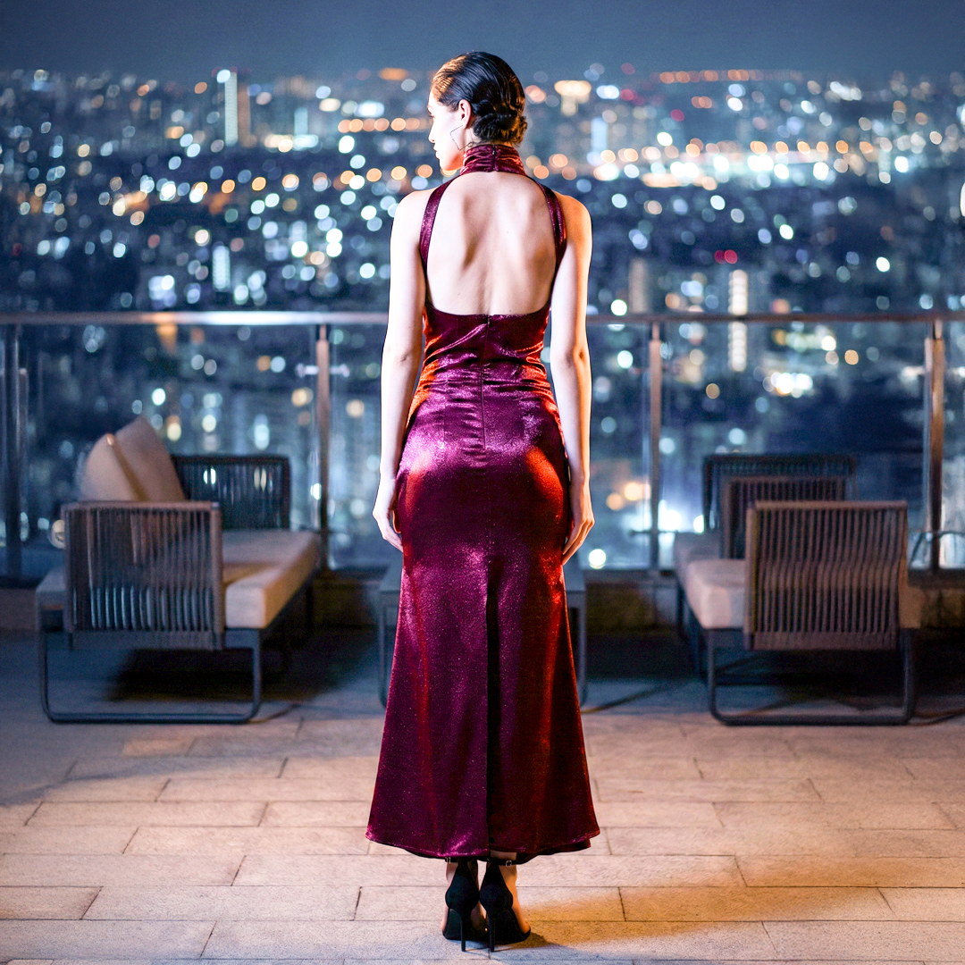 Back view of woman wearing a burgundy silk satin halter neck maxi dress with an elegant floor-length silhouette