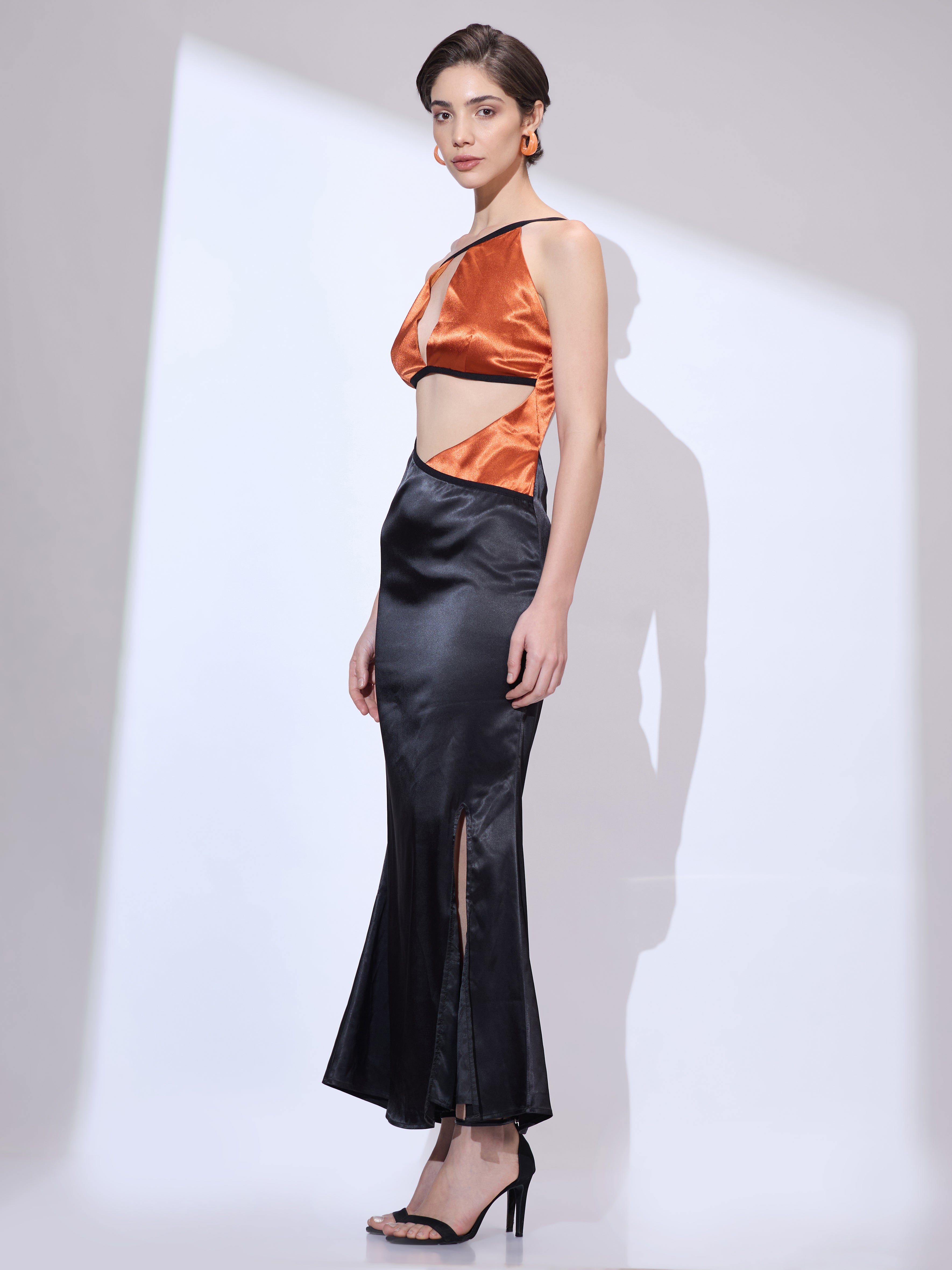 Image of Side angle of woman in a black silk satin cowl neck maxi dress with graceful movement