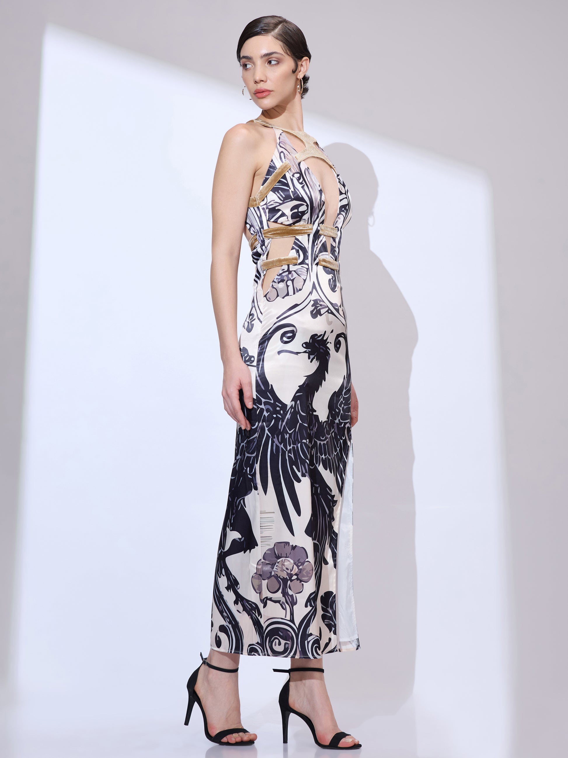 Standing at a side angle and looking right in a designer maxi gown with a black and white dragon print and a plunge neckline