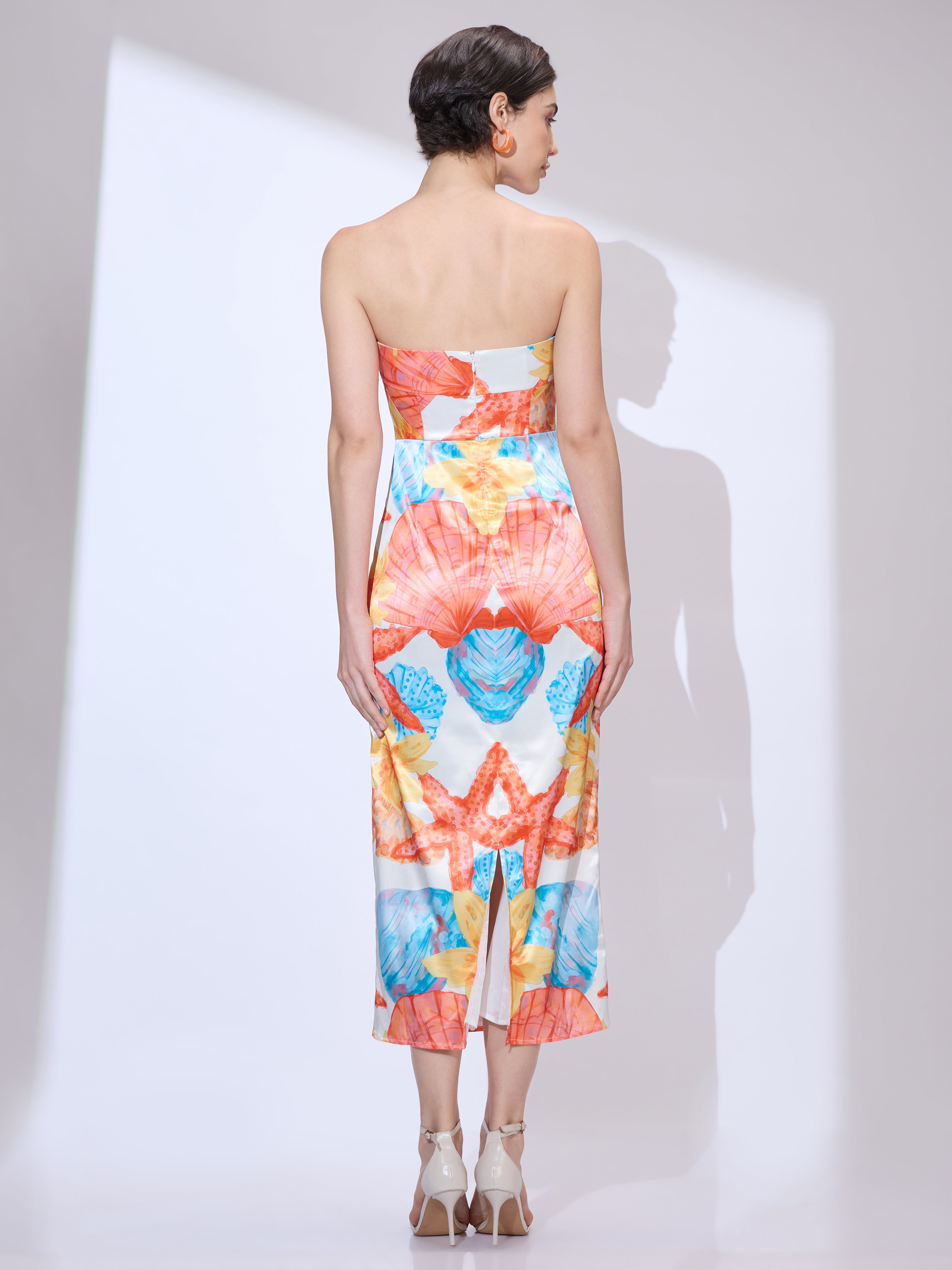 Image of Back view of woman wearing a colorful strapless midi from ladies resort wear with vibrant seashell and starfish print