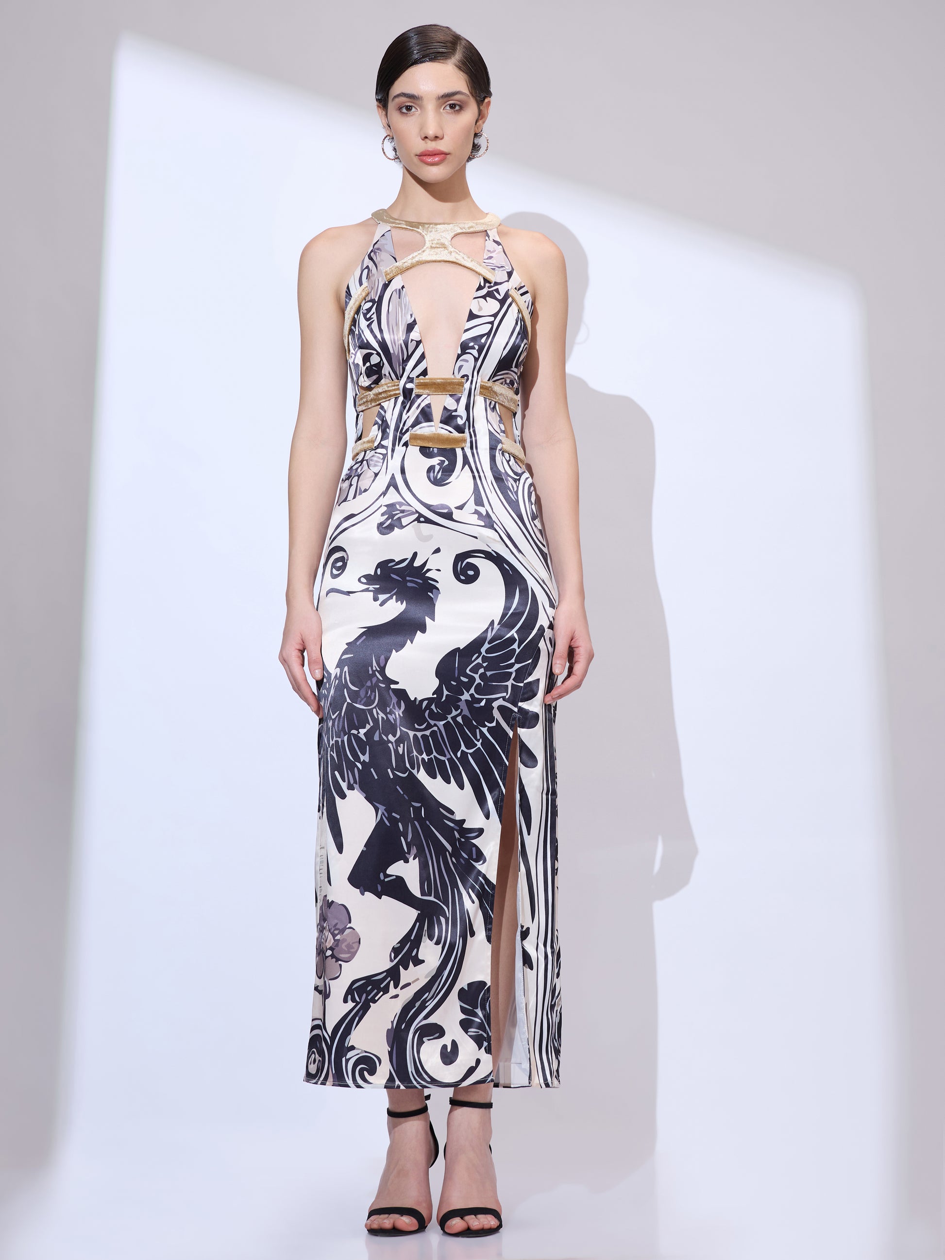 Standing front in a maxi halter neck dress with a black and white dragon print and a plunge neckline