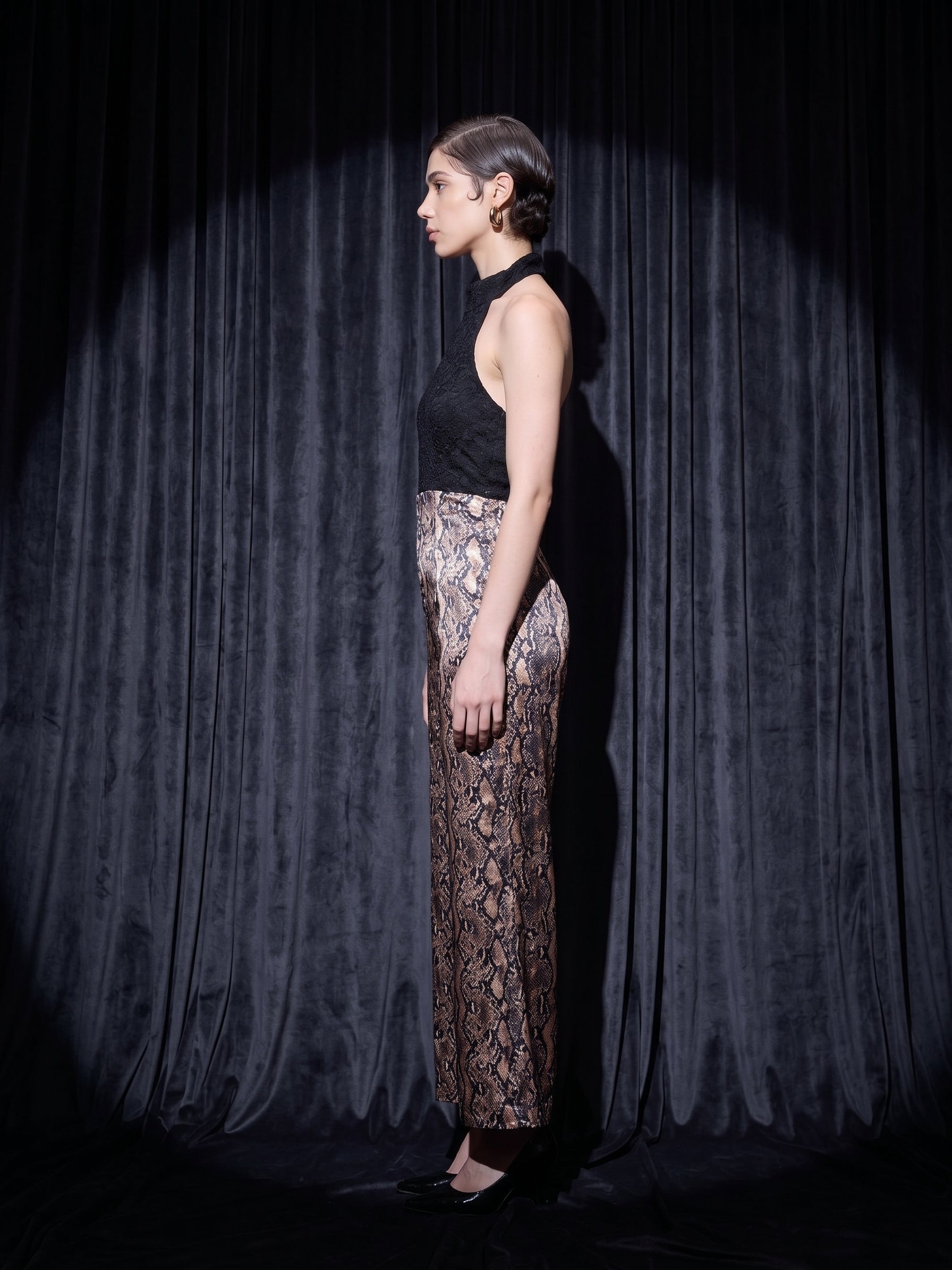 Image of Viper halter wide-leg jumpsuit in black and gold metallic snakeskin, side view — INHAUTECOUTURE